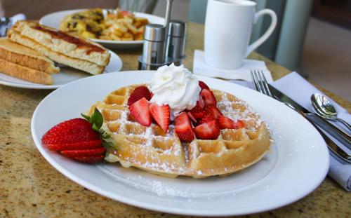 a waffle with strawberries and whipped cream on a table at DoubleTree Suites by Hilton Melbourne Beach Oceanfront in Melbourne