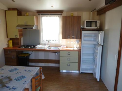 a small kitchen with a refrigerator and a microwave at Auberge des Etangs in Roussent
