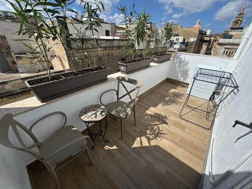a balcony with chairs and plants on a roof at Bentley Floriana Suites in Il-Furjana