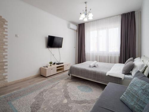 a bedroom with two beds and a flat screen tv at Апартамент с восхитительным видом на горы и огни города in Almaty