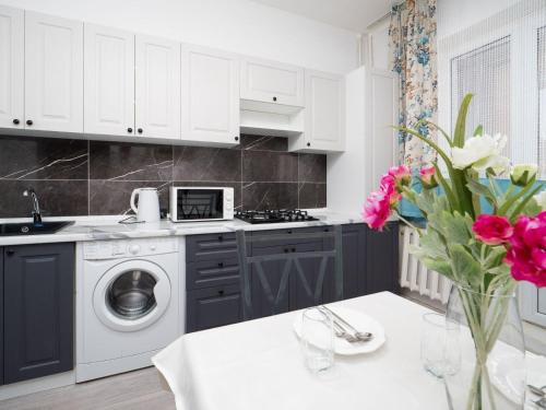 a kitchen with a washing machine and a table with flowers at Апартамент с восхитительным видом на горы и огни города in Almaty