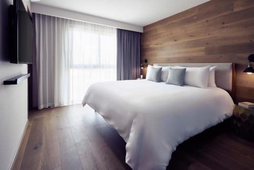 a bedroom with a large white bed and a window at Frida by Viadora in Mexico City