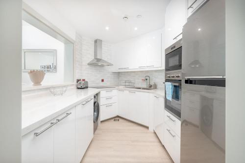 a white kitchen with white cabinets and a large window at Free housekeeping visits during your stay - StayShort - Elegant 1BR Haven for 3 in Palm Jumeirah in Dubai