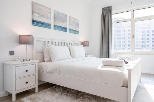 a white bedroom with a white bed and a window at Free housekeeping visits during your stay - StayShort - Elegant 1BR Haven for 3 in Palm Jumeirah in Dubai