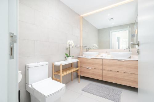 a white bathroom with two sinks and a toilet at Free housekeeping visits during your stay - StayShort - Elegant 1BR Haven for 3 in Palm Jumeirah in Dubai