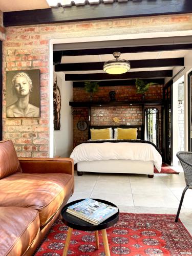 a bedroom with a bed and a brick wall at The Secret Garden Hideaway in Mossel Bay