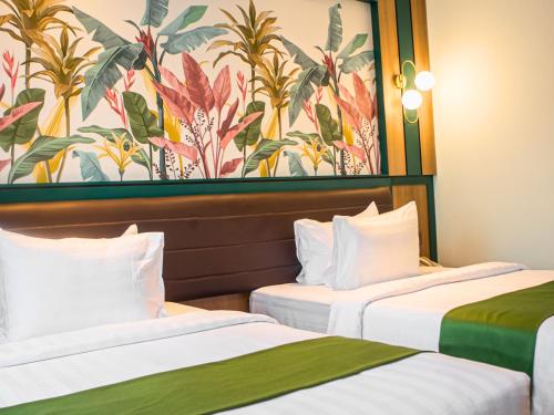 two beds in a hotel room with a mural at Bona Ventura Hotel & Skybar in Tanjung Pinang 
