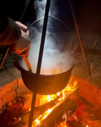 a person cooking in a pot over a fire at Valea Salbatica in Şinca Nouă