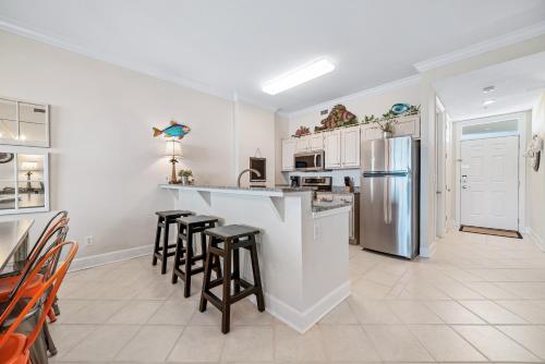 a kitchen with bar stools and a refrigerator at Grand Pointe Unit 706 in Orange Beach