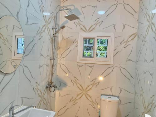 a bathroom with a shower and a sink and a mirror at Tile House Apartments Gunjur Kolkoch in Gunjur