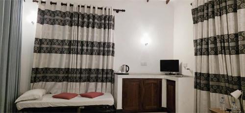 a room with a bed and a television and curtains at Lake View Resort by TropiCube in Pamunugama