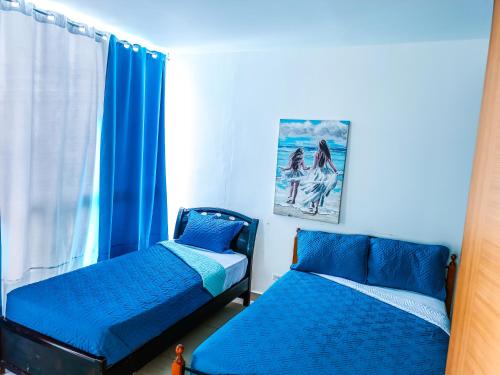 a bedroom with two beds with blue sheets and a window at Golden Sun Penthouse VIP in Playa Blanca