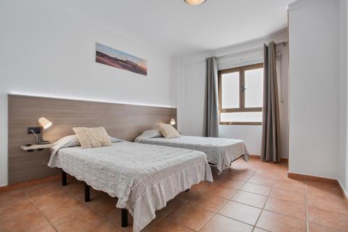 a room with two beds and a window at Corralejo Ian’s Dreams in Corralejo