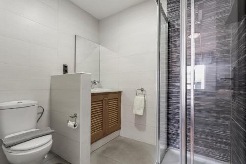 a white bathroom with a toilet and a shower at Corralejo Ian’s Dreams in Corralejo