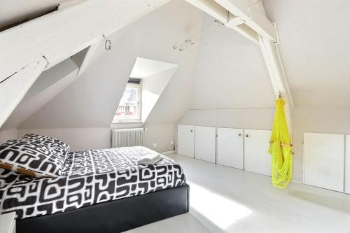 una camera da letto con un letto bianco e nero in una soffitta di Le Repaire du Lion - Quadruplex - 10 voyageurs a Belfort