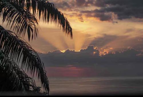 a sunset over the ocean with a rainbow in the sky at Seaview studio's, free breakfast & park tour in Quepos