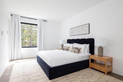 a white bedroom with a large bed and a window at Blue Jay Villa by Rove - Family Home with Heated Pool Sauna & Gym in East Hampton