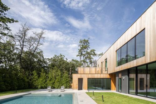 an external view of a house with a swimming pool at Blue Jay Villa by Rove - Family Home with Heated Pool Sauna & Gym in East Hampton