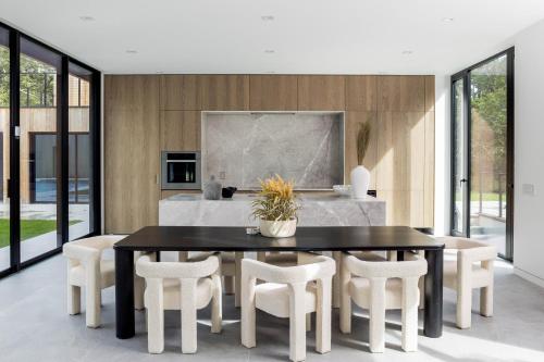 a dining room with a black table and white chairs at Blue Jay Villa by Rove - Family Home with Heated Pool Sauna & Gym in East Hampton