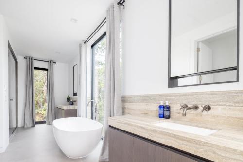 a bathroom with a large white tub and a sink at Blue Jay Villa by Rove - Family Home with Heated Pool Sauna & Gym in East Hampton