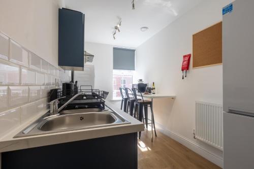 a kitchen with a sink and a table with chairs at St James Court Aparthotel in Derby