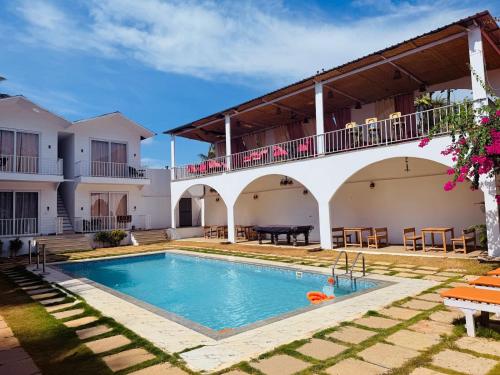 a villa with a swimming pool and a house at Beachwaves cottages by Tvessa in Morjim