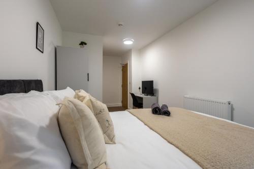 a bedroom with a white bed with two pairs of shoes on it at St James Court Aparthotel in Derby