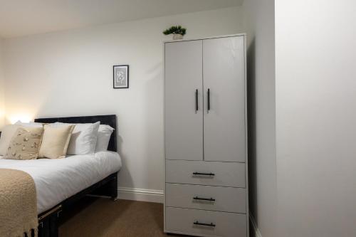 a bedroom with a white cabinet next to a bed at St James Court Aparthotel in Derby