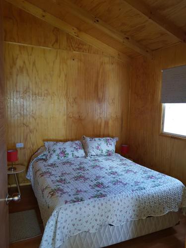 a bedroom with a bed in a wooden room at CABAÑAS RINCON SOLEADO, Chile Chico in Chile Chico
