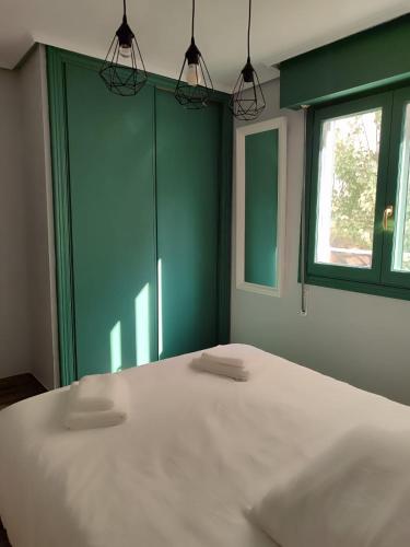 a bedroom with a large white bed with a green wall at El Soto in Villarcayo