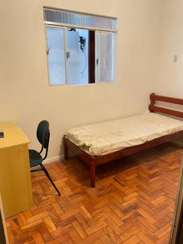 a room with a bed and a chair and a window at Casa em área nobre de Juiz de Fora in Juiz de Fora