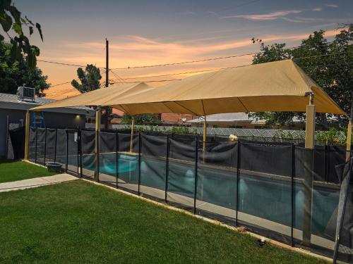 a large tan umbrella next to a swimming pool at Remodeld5BR Modern Retreat with Covered Pool in El Paso