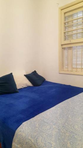 a bedroom with a bed with blue sheets and a window at Casa do Pescador in Bertioga