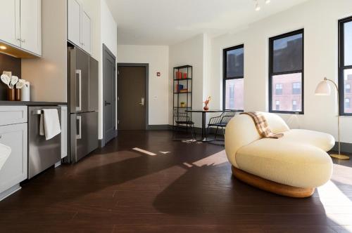 a living room with a white chair in a kitchen at Remodeled 2BR Downtown Near Acrisure Stadium in Pittsburgh