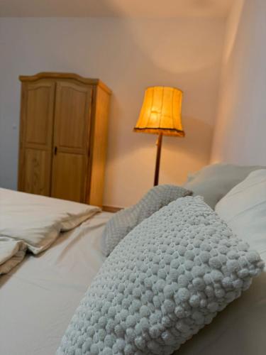 a white blanket laying on a bed with a lamp at Gemütliches Buchen Zimmer mit Gemeinschaftsbad in Karlsruhe
