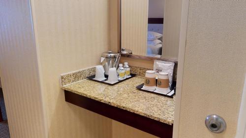 a bathroom counter with bottles and a mirror at Sheraton West Des Moines in West Des Moines