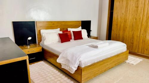 a bedroom with a large bed with red pillows at Résidence FARASELAA in Dakar
