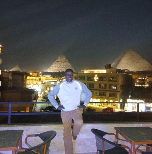 a man standing on a rooftop with pyramids in the background at Red Pyramids Hotel in Cairo