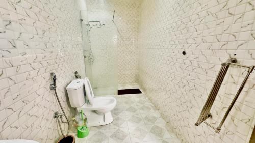 a white bathroom with a toilet and a shower at Résidence FARASELAA in Dakar