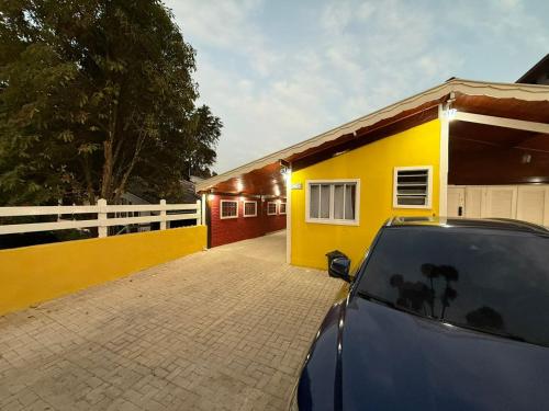 a car parked in front of a yellow house at Memoriá in Campos do Jordão
