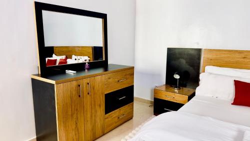 a bedroom with a bed with a mirror and a dresser at Résidence FARASELAA in Dakar