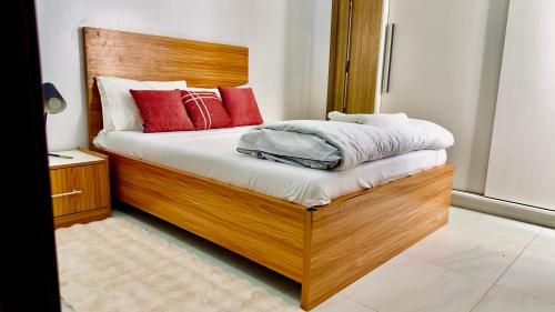 a bedroom with a wooden bed with red pillows at Résidence FARASELAA in Dakar