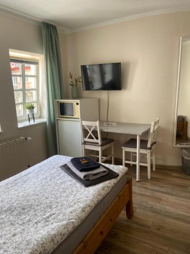 a bedroom with a bed and a desk and a television at Altstadt Pension Herborn in Herborn