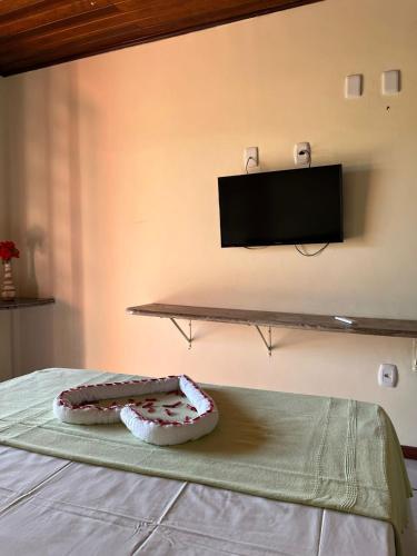 a cake sitting on a bed with a tv on the wall at Hotel Recanto Do Sol in Porto Seguro