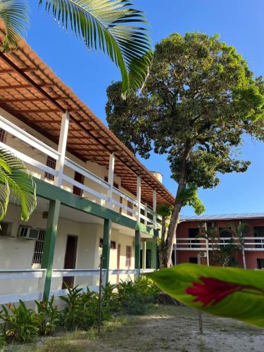 a building with a tree in front of it at Hotel Recanto Do Sol in Porto Seguro