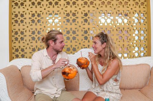 a man and a woman sitting on a couch eating fruit at Exotica Bungalows -Hikkaduwa in Hikkaduwa