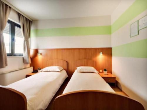 2 camas en una habitación con rayas verdes y blancas en Motel Šibenik, en Šibenik