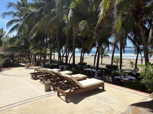 a row of benches on a beach with palm trees at Puertas Paraíso Hotel boutique in Zihuatanejo
