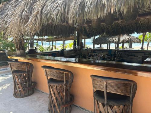 a bar with two chairs and a straw roof at Puertas Paraíso Hotel boutique in Zihuatanejo