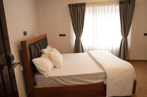 una camera da letto con un letto con lenzuola bianche e una finestra di Pallakki Comforts Chikmagalur a Attigundi